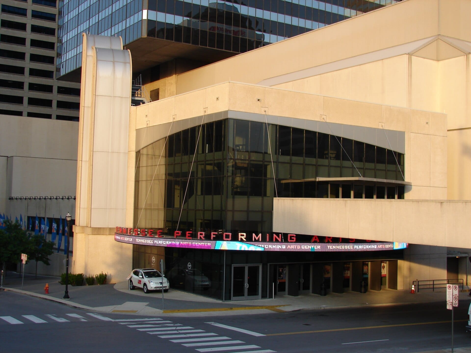 La fachada moderna del Tennessee Performing Arts Center en el centro de Nashville, con grandes ventanales de cristal y un elegante marquesina sobre la entrada.