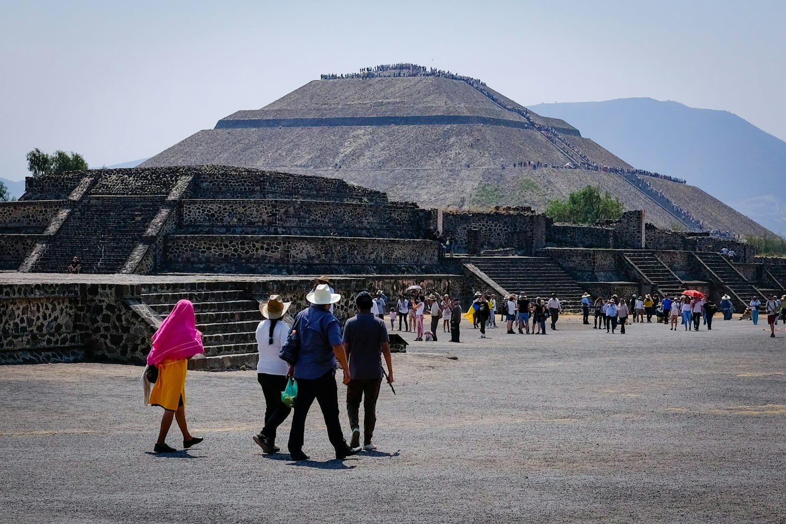 Vista da Pirâmide do Sol de Teotihuacán com multidões de visitantes caminhando pela Avenida dos Mortos sob céu limpo