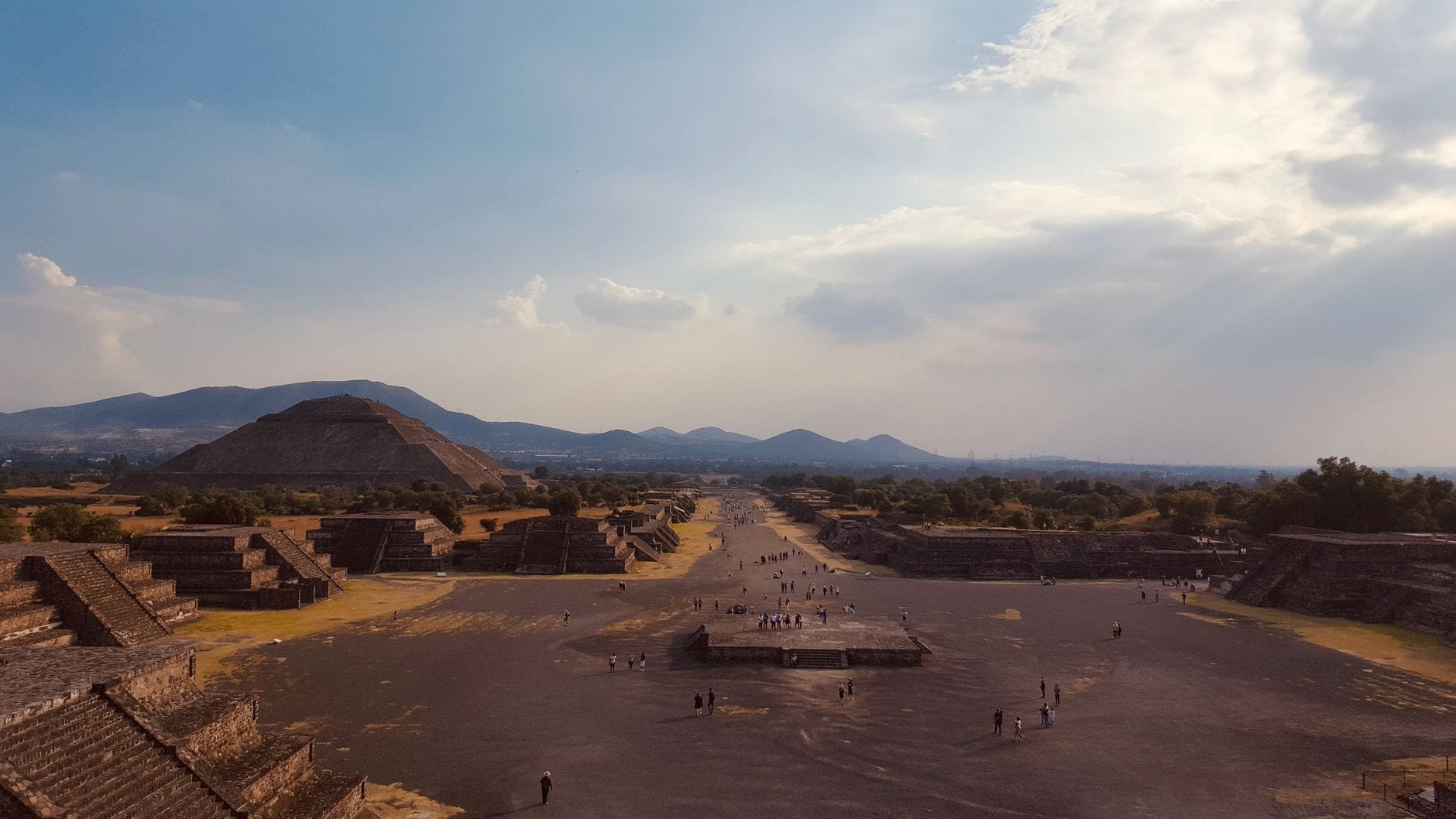 Vista panoramica del Viale dei Morti a Teotihuacán con la Piramide del Sole e le piramidi circostanti sotto un cielo spettacolare.