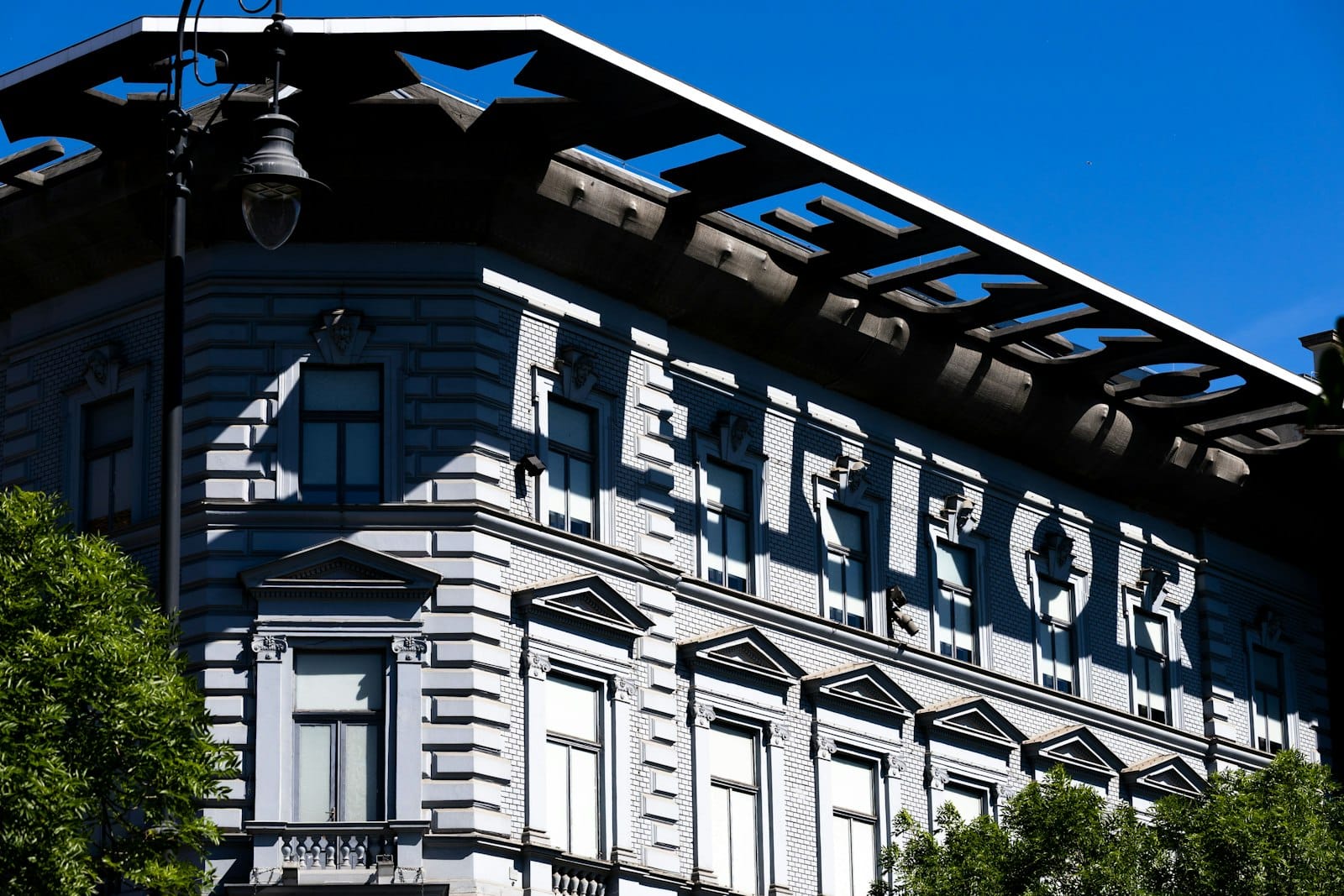 Außenansicht des House of Terror Museums in Budapest mit dem markanten Schriftzug 'TERROR' an der Fassade vor strahlend blauem Himmel.