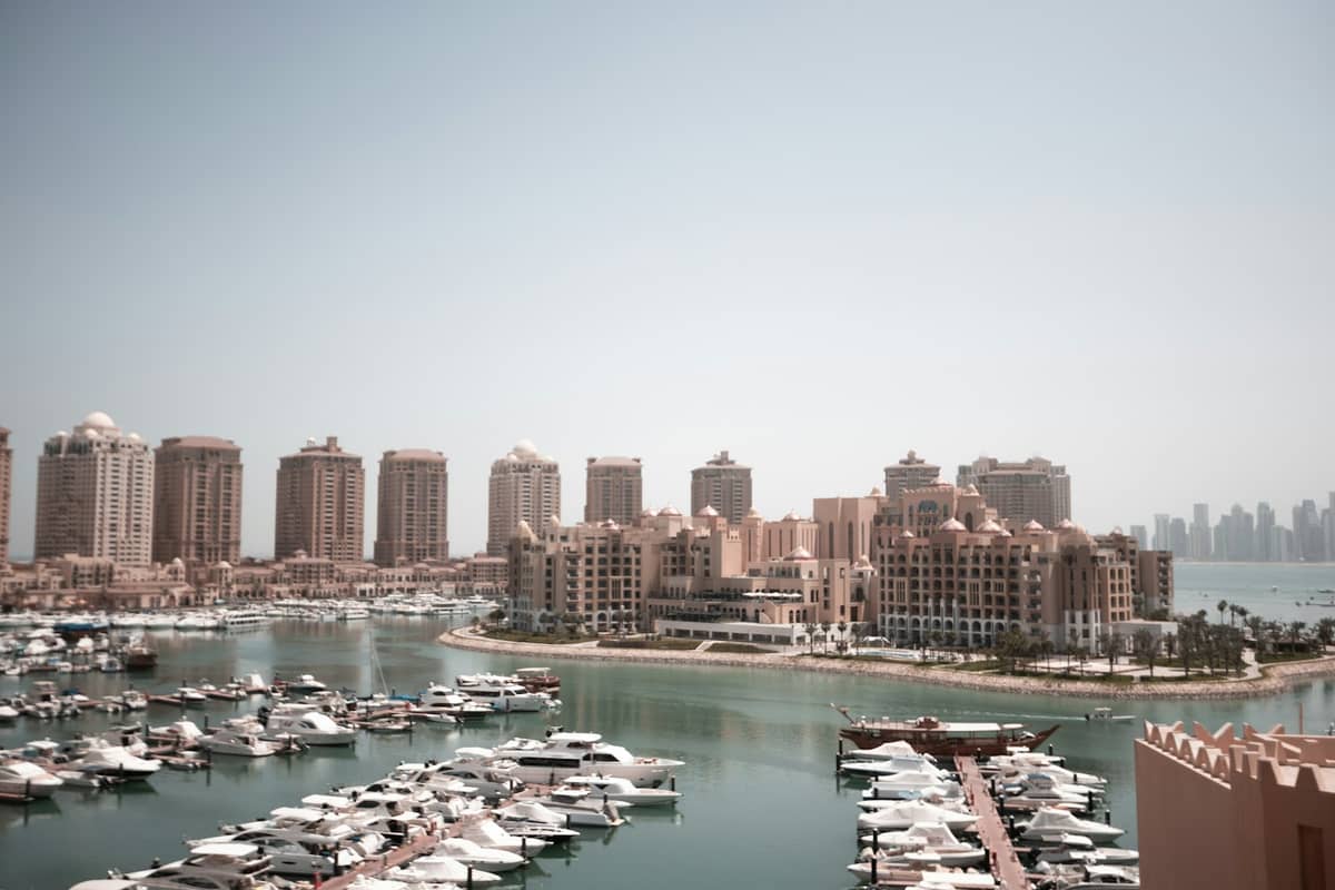 Weitläufiger Blick auf die Porto-Arabia-Marina von The Pearl-Qatar mit festgemachten Yachten und markanten Wohnhochhäusern entlang der Uferpromenade.
