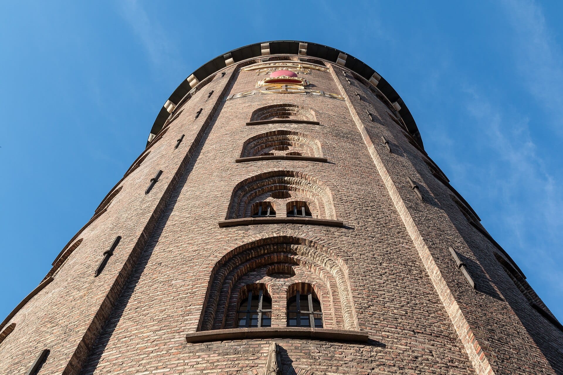 Vista dal basso della facciata in mattoni e delle finestre ad arco della Round Tower su un cielo azzurro limpido di Copenaghen.