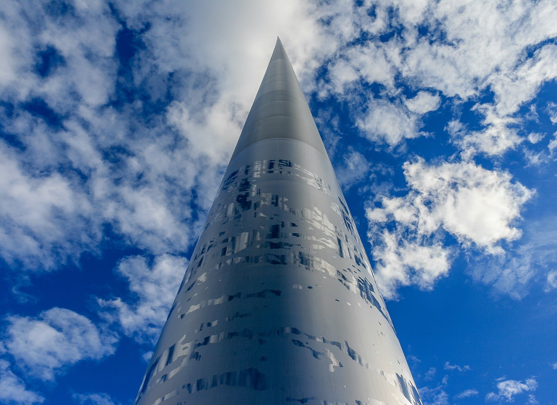 Vista verso l'alto del monumento Spire of Dublin contro un cielo azzurro brillante con nuvole bianche sparse durante il giorno.