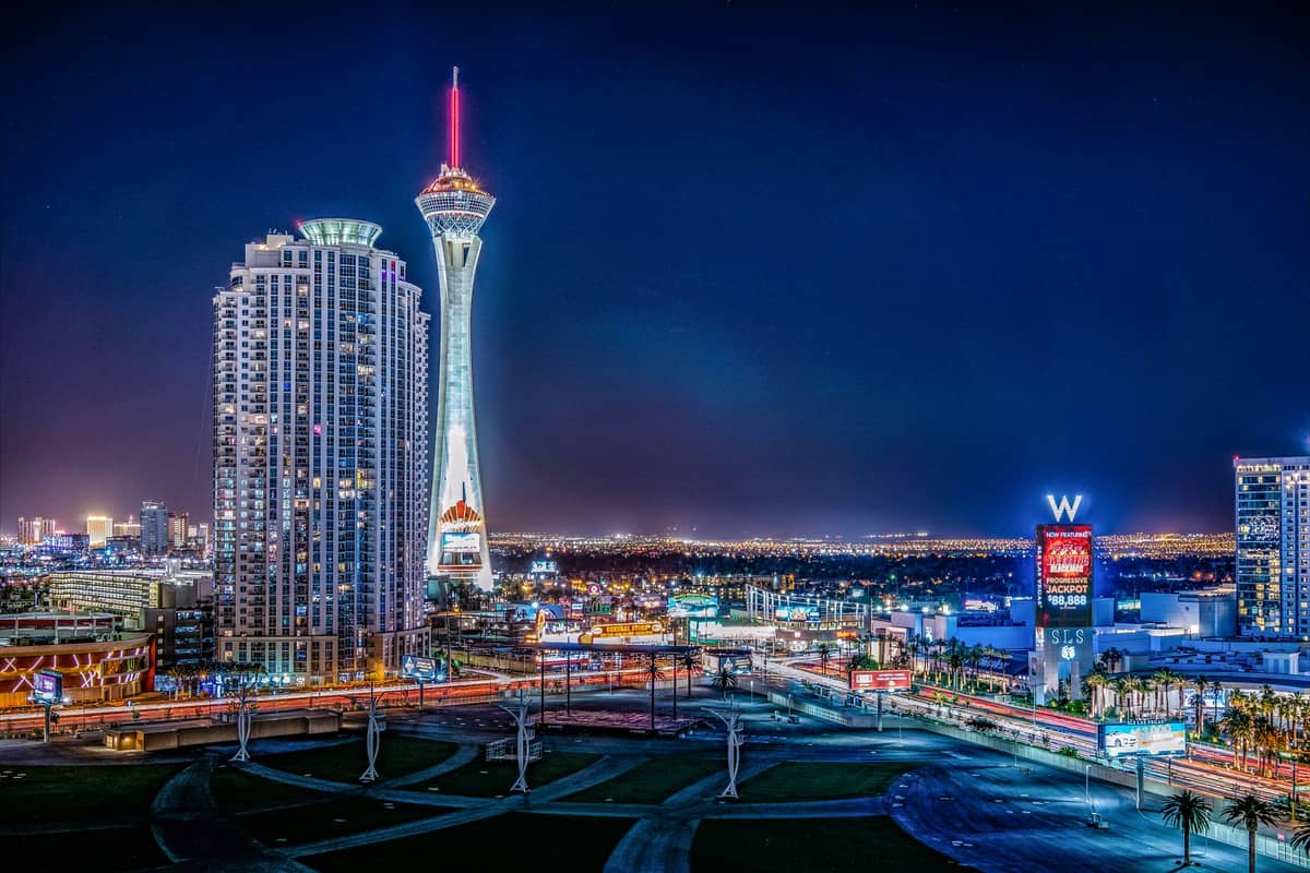 Vue nocturne du STRAT Hotel, Casino & SkyPod à Las Vegas, avec sa tour d'observation illuminée qui s'élève au-dessus de la ville et les lumières au néon en contrebas.