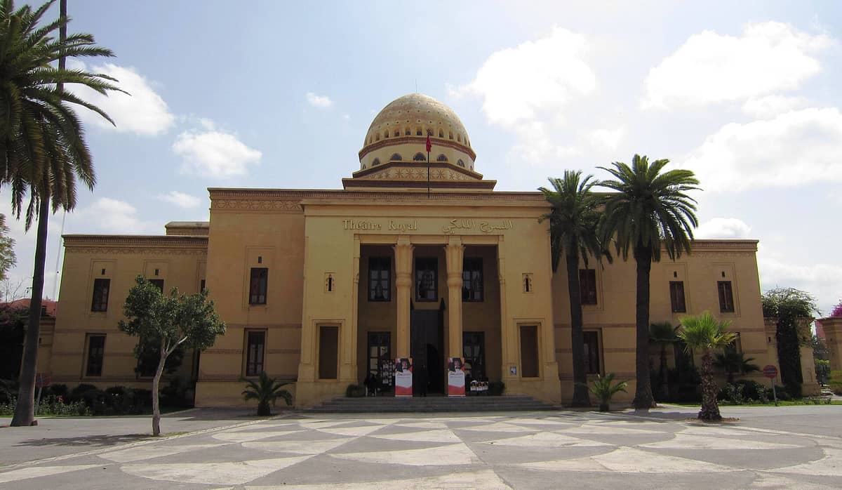 ทางเข้าอันยิ่งใหญ่ของ Théâtre Royal de Marrakech พร้อมเสา โดม และต้นปาล์ม ท่ามกลางท้องฟ้าสดใสในย่าน Gueliz