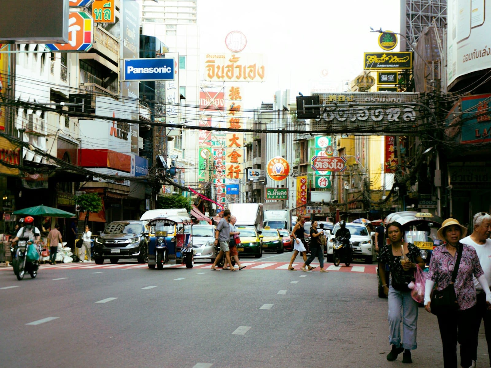 Rua movimentada do bairro chinês Yaowarat em Bangkok com trânsito, letreiros de neon e multidão entre barracas de comida de rua
