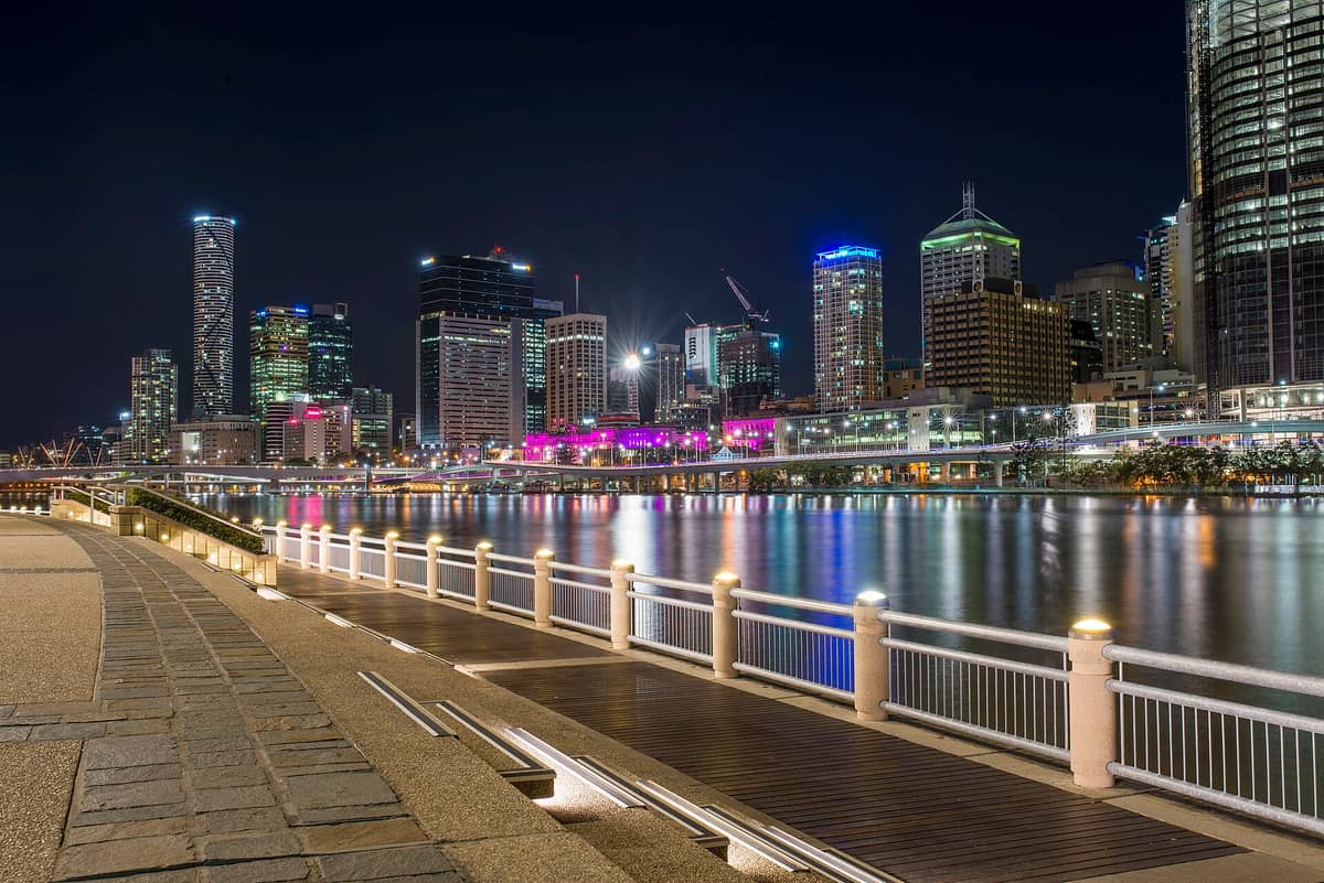 Horizonte nocturno de Brisbane visto desde South Bank, con los edificios iluminados y sus reflejos de colores sobre el río Brisbane.