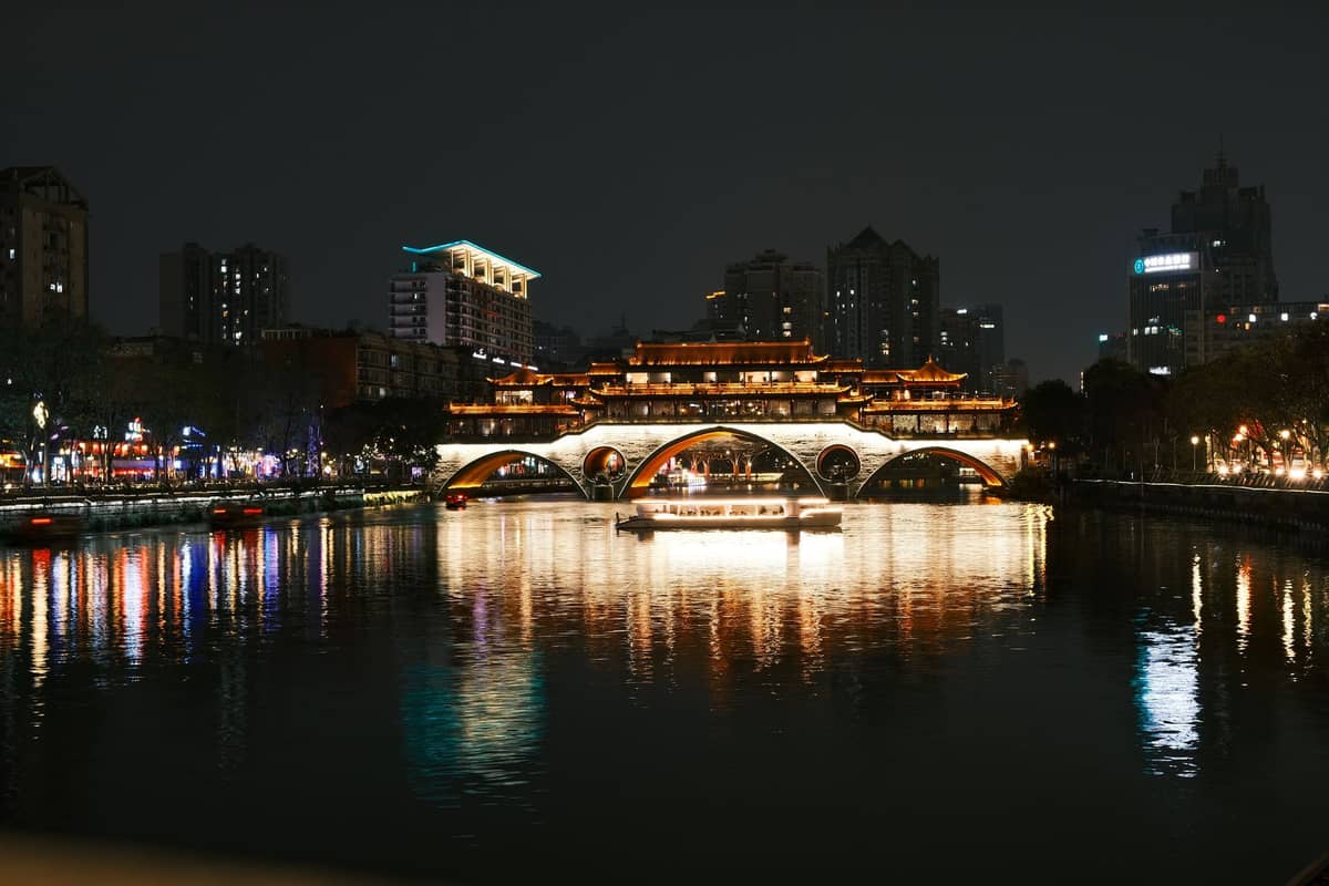 Nächtlicher Blick auf die Anshun-Brücke in Chengdu, festlich beleuchtet und im Jin-Fluss gespiegelt, mit der Stadtkulisse im Hintergrund.