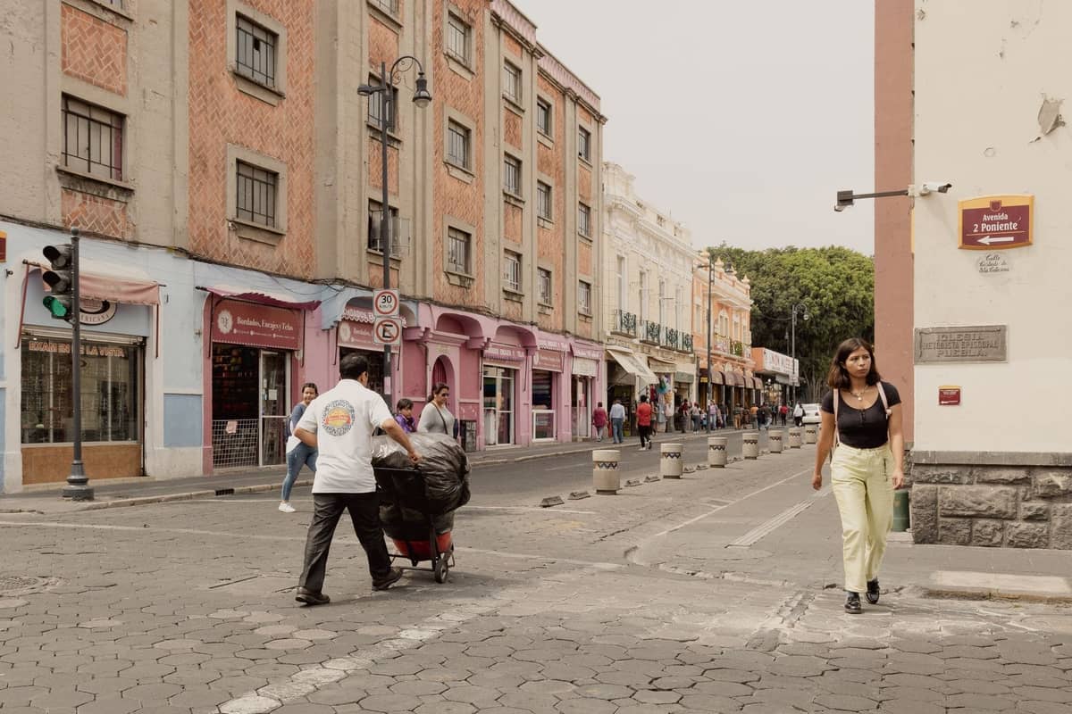 Belebte Stadtstraße in Guadalajara mit Gebäuden aus dem frühen 20. Jahrhundert, Fußgängern und bunten Geschäftsfronten in einer lebhaften Nachbarschaft.