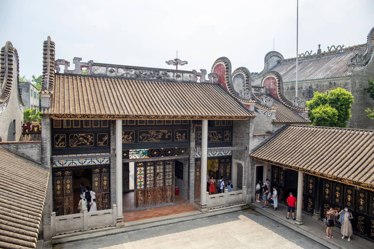 Courtyard of the Chen Clan Ancestral Hall in Guangzhou, showing intricate rooflines, decorative details, and visitors exploring the historic site.