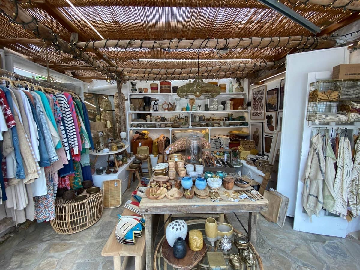 Artisan market stall with ceramics, baskets, clothing, and crafts under a rustic wooden roof in Ibiza.