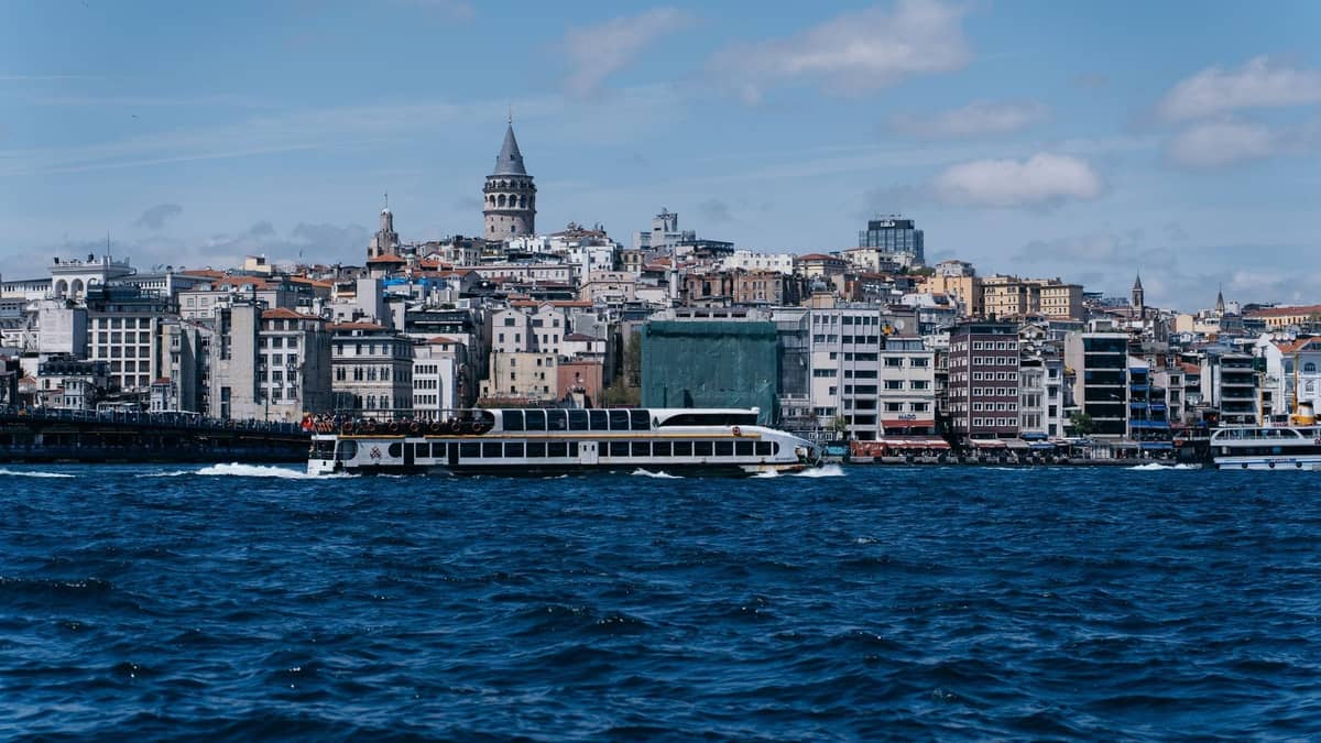Ferry traversant le Bosphore avec la Tour de Galata et le paysage urbain d'Istanbul en arrière-plan par une journée claire.