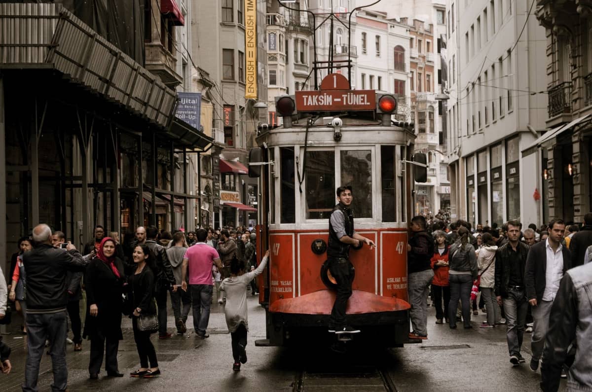 L'avenue Istiklal d'Istanbul avec un tramway rouge historique, animée de nombreux piétons se promenant dans cette rue vivante et pleine d'atmosphère, bordée de grands immeubles.