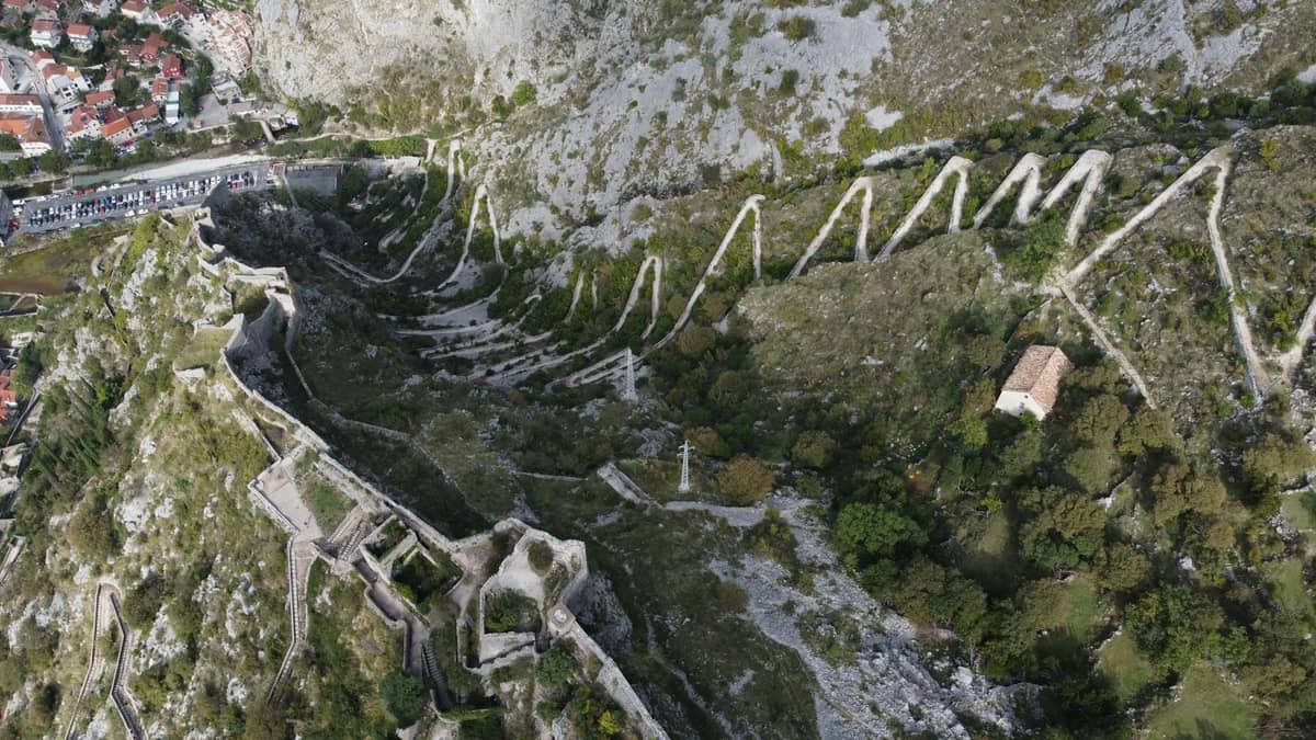 Aerial view of Kotor's fortress walls zigzagging up the steep hillside offering panoramic views of the Old Town and surrounding mountains.