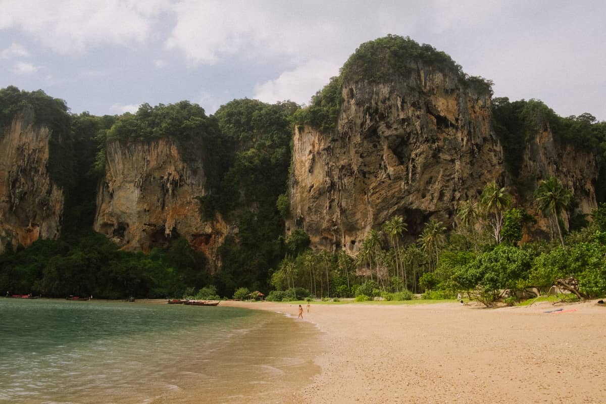Railay Beach in Krabi, Thailand – goldener Sand, türkisfarbenes Wasser und dramatische Kalksteinfelsen, bedeckt mit sattem Dschungelgrün.
