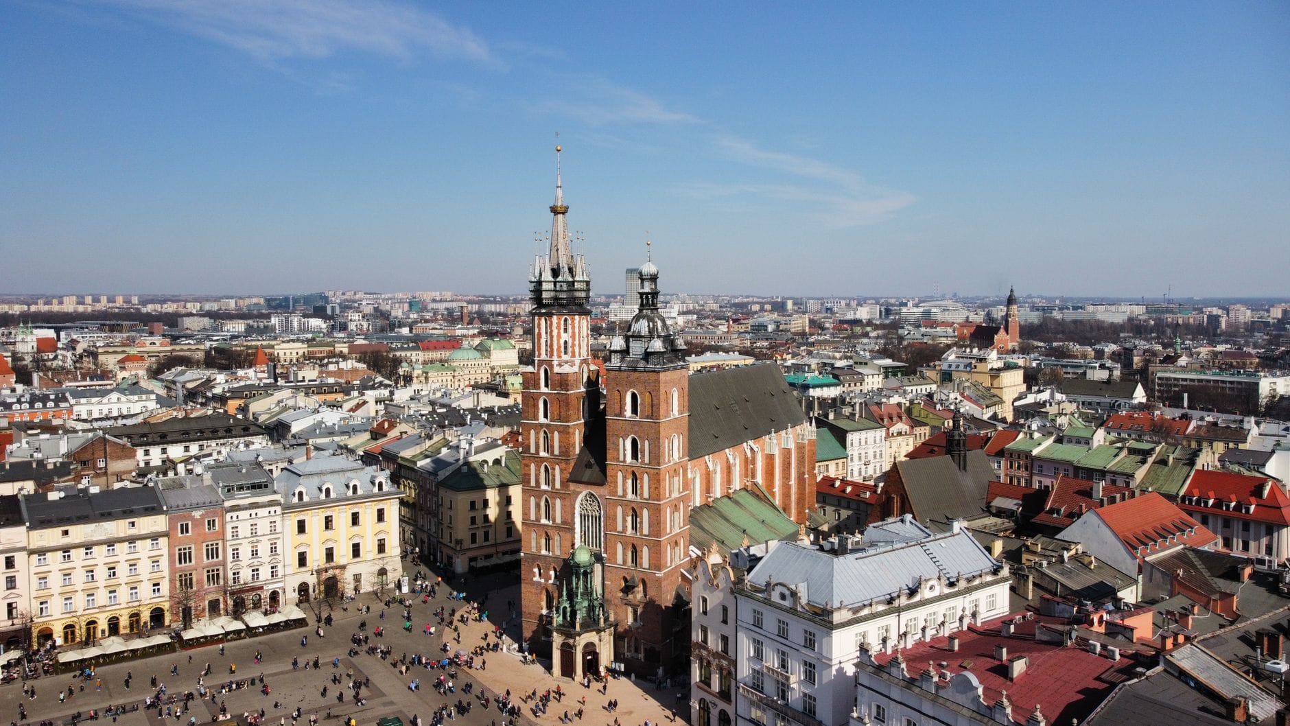 มุมมองทางอากาศของ Rynek Główny ในเมือง Kraków พร้อมมหาวิหาร St. Mary's อาคารประวัติศาสตร์ และผู้คนที่กำลังเดินใน จัตุรัสตลาดหลัก