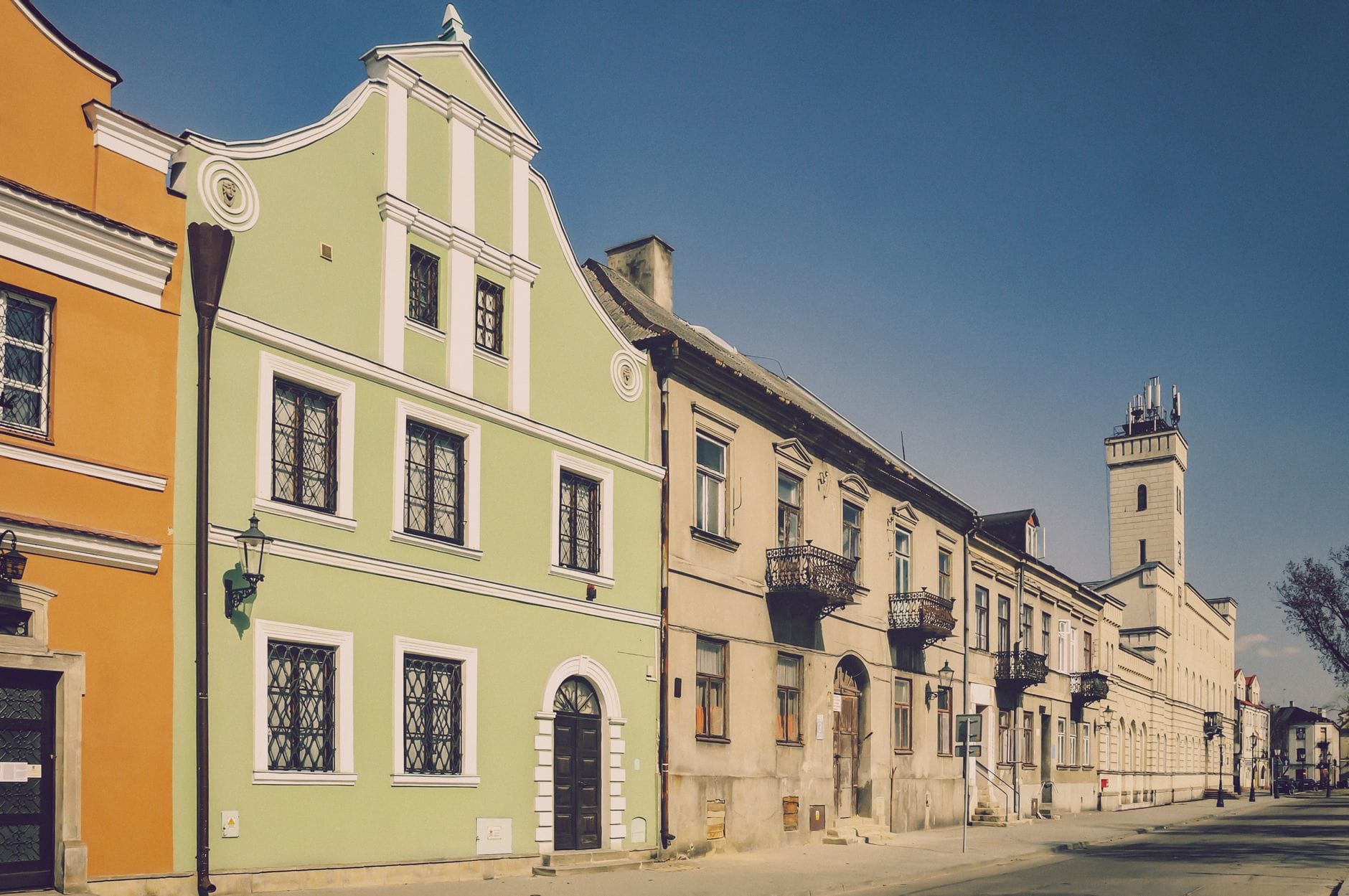 อาคารประวัติศาสตร์สีพาสเทลและโบสถ์ยิวเรียงรายตามถนนสงบในย่าน Kazimierz เมือง Kraków ใต้ท้องฟ้าสีฟ้าแจ่มใส