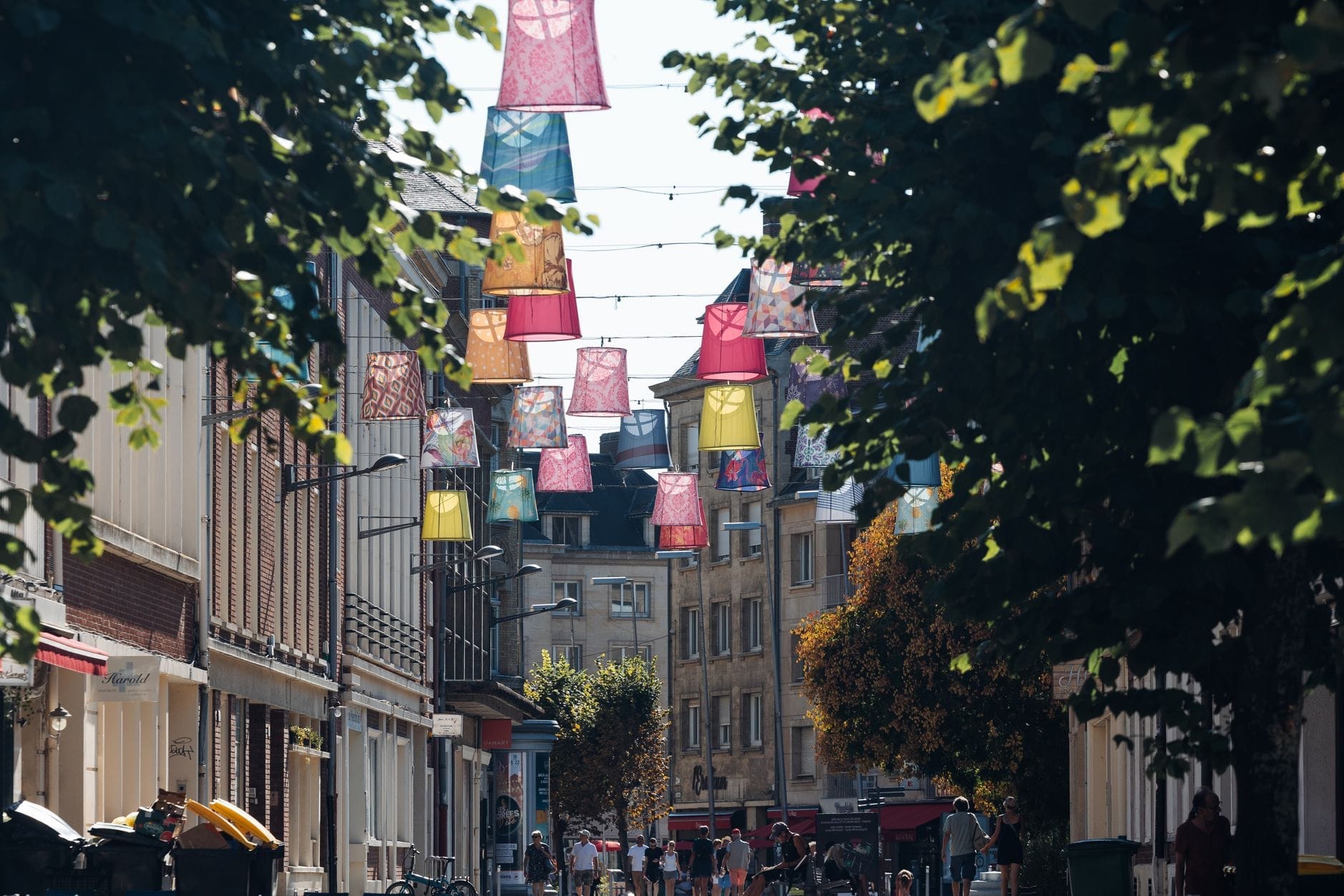 Kolorowe lampiony wiszące nad deptakiem obsadzonym drzewami i pełnym ludzi w tętniącej życiem scenie miejskiej