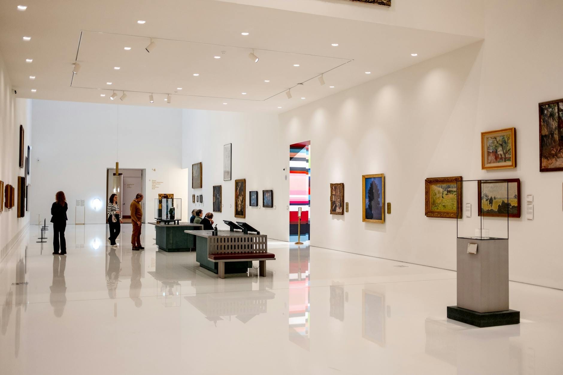 Galerie d'art moderne à Lisbonne avec des murs blancs, des peintures et des visiteurs admirant des œuvres d'art dans une salle spacieuse et bien éclairée.