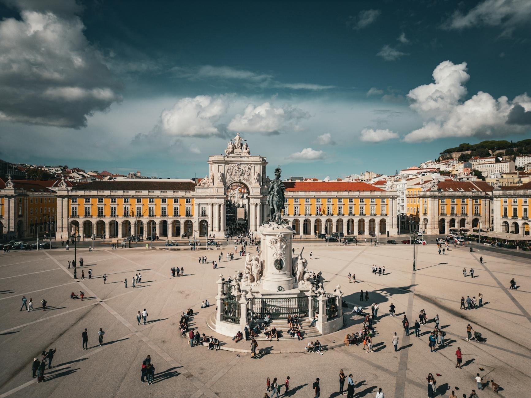 Praça do Comércio au centre-ville de Lisbonne avec l'Arc de la Rua Augusta, une statue et des personnes se promenant sur la grande place par une journée ensoleillée.