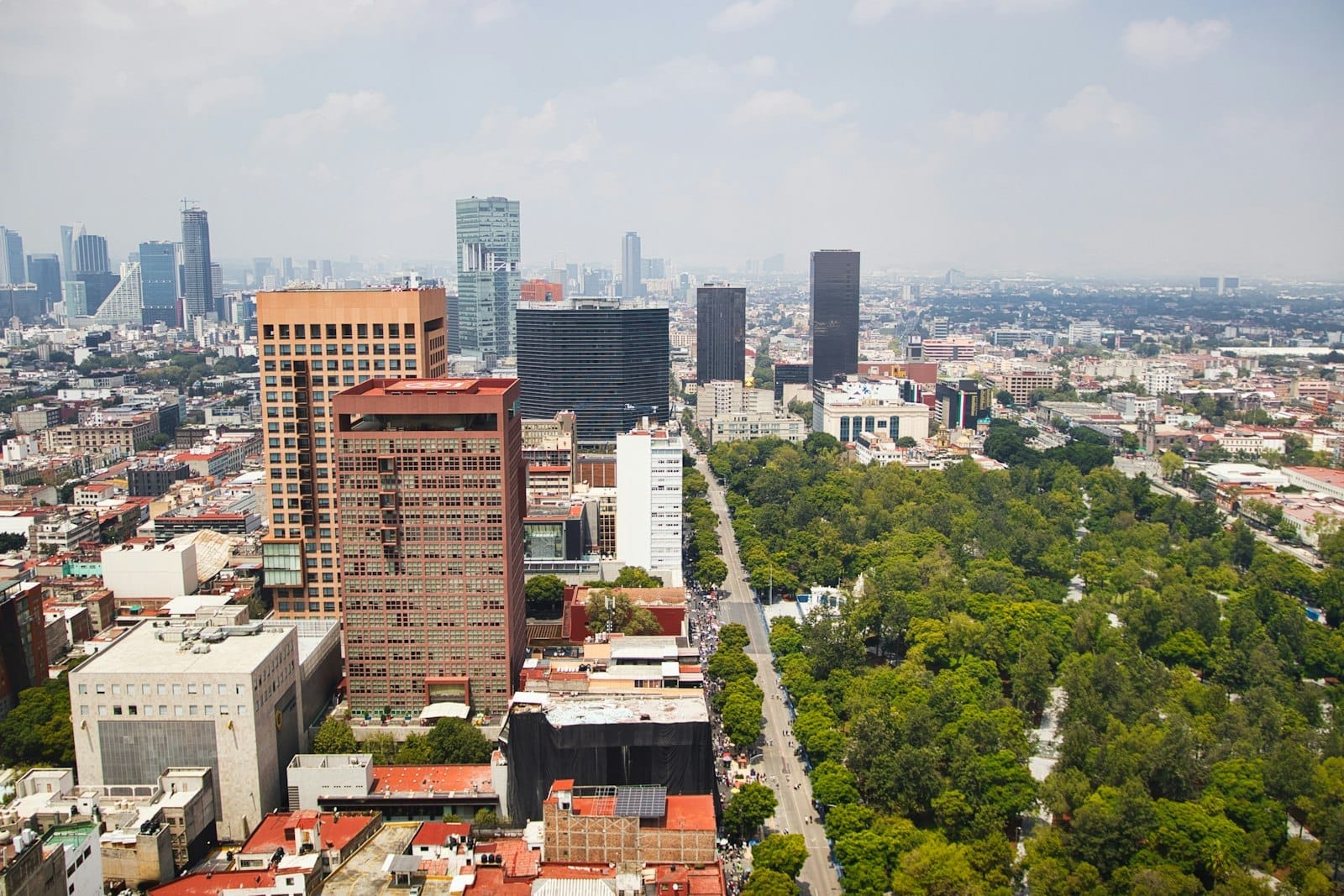 Vista aérea da Cidade do México mostrando a grande área verde do Parque Chapultepec ao lado de arranha-céus modernos e ruas urbanas ao redor.