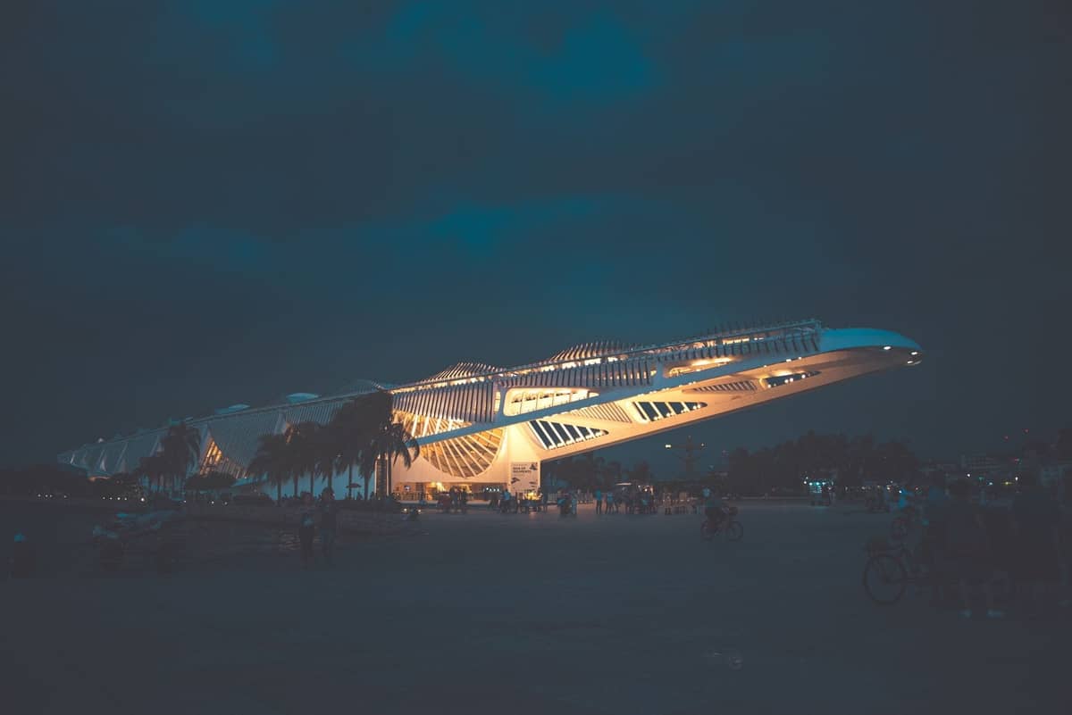 Night view of the illuminated Phillip and Patricia Frost Museum of Science in Downtown Miami with people and palm trees in the foreground