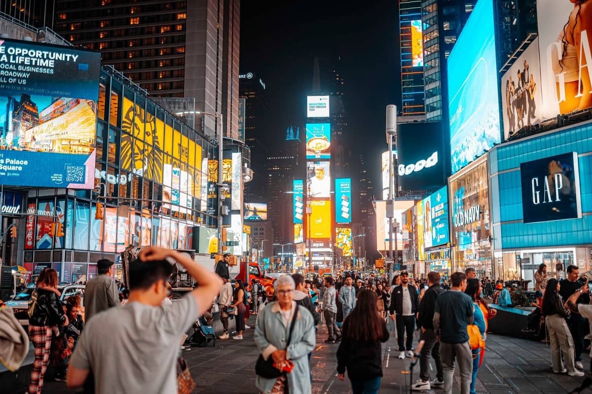 Menschenmassen am Times Square bei Nacht mit hellen Werbetafeln und Lichtern, die die lebhafte Energie des New Yorker Nachtlebens einfangen.