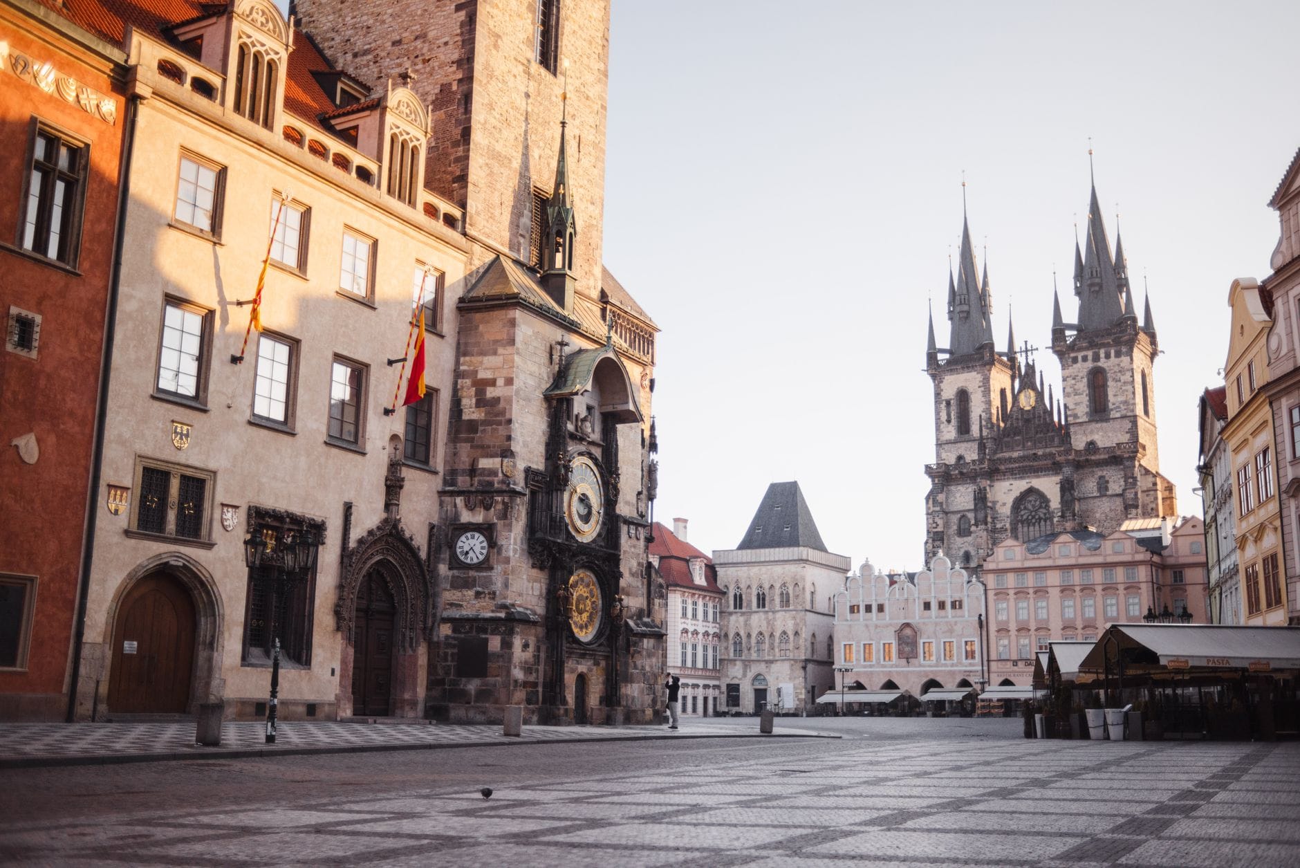 Blick auf den Altstädter Ring in Prag mit der Astronomischen Uhr, bunten historischen Fassaden und den Zwillingstürmen der Tyn-Kirche im Morgenlicht.