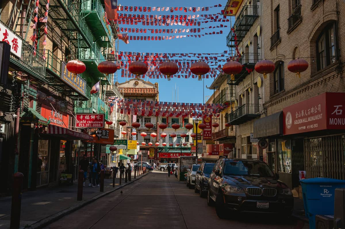 Straßenansicht in San Francisco Chinatown mit roten Laternen, die oben hängen, und traditioneller chinesischer Architektur auf beiden Seiten.