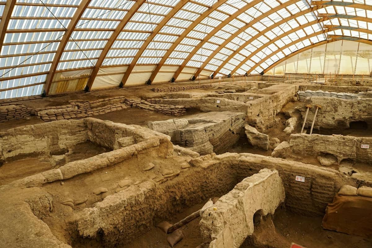 Vista interior del yacimiento arqueológico de Akrotiri en Santorini, con ruinas antiguas y zonas de excavación bajo un techo protector.