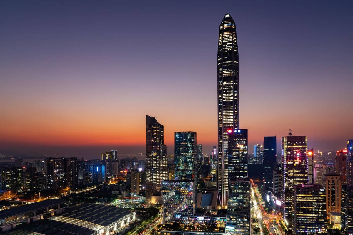 Vista ao pôr do sol do moderno horizonte de Shenzhen com arranha-céus altos, incluindo o Ping An Finance Center, e as luzes da cidade começando a iluminar a paisagem urbana.