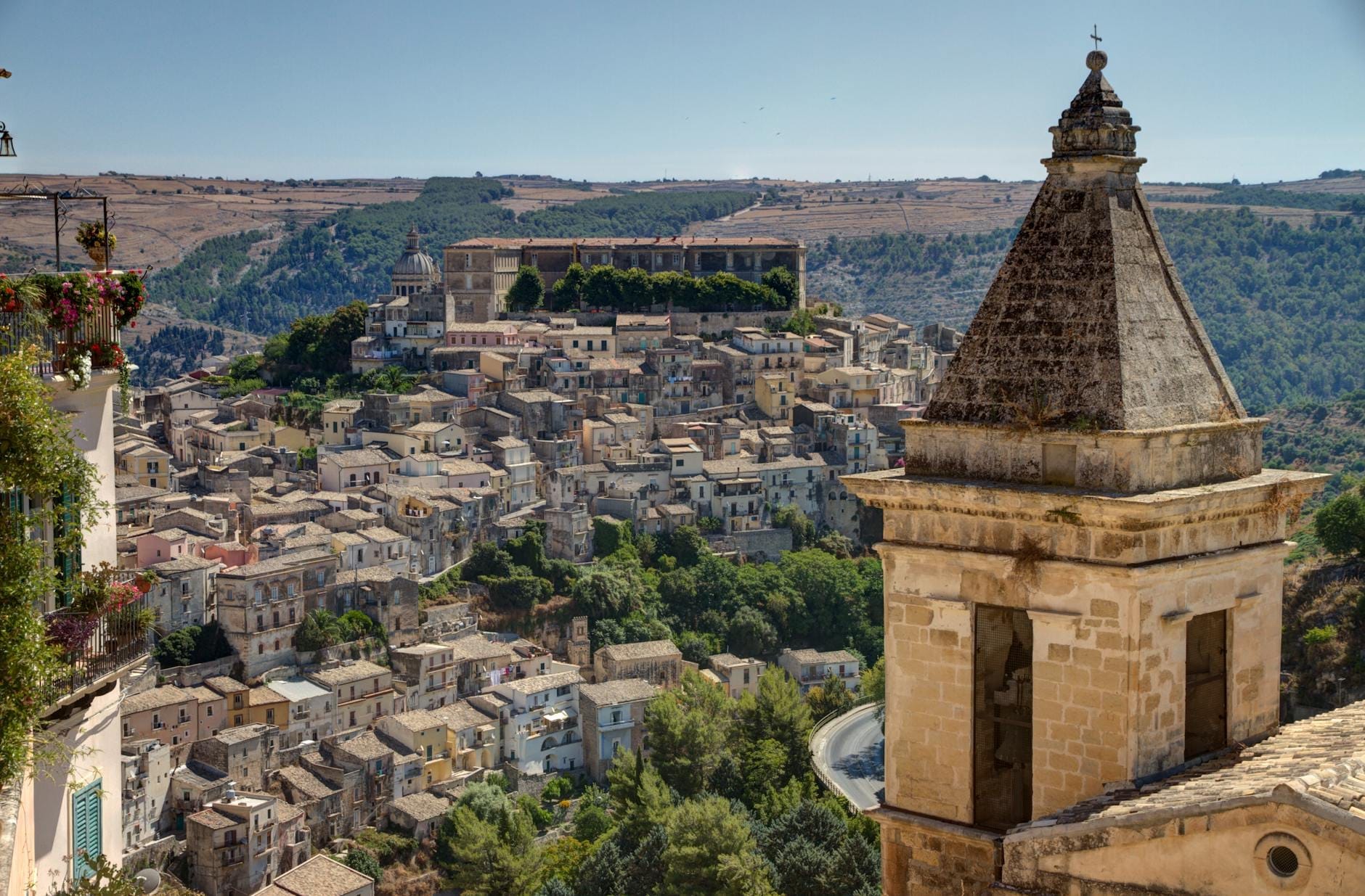 Tagesansicht von Ragusa Ibla mit Barockgebäuden und Dächern, umgeben von sizilianischen Hügeln und Landschaft.