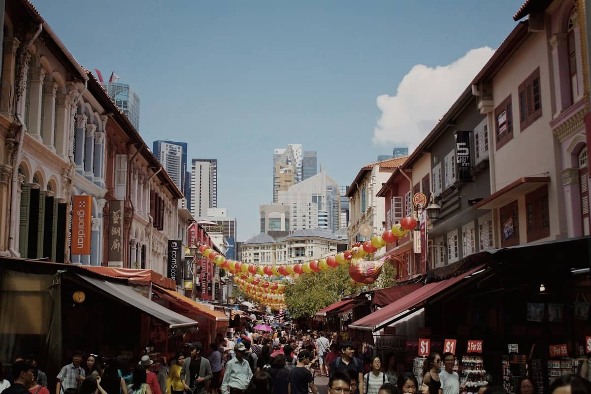 Busy street scene in Singapore Chinatown with historic shophouses, hanging lanterns, and crowds of people, showcasing the vibrant cultural neighbourhood.