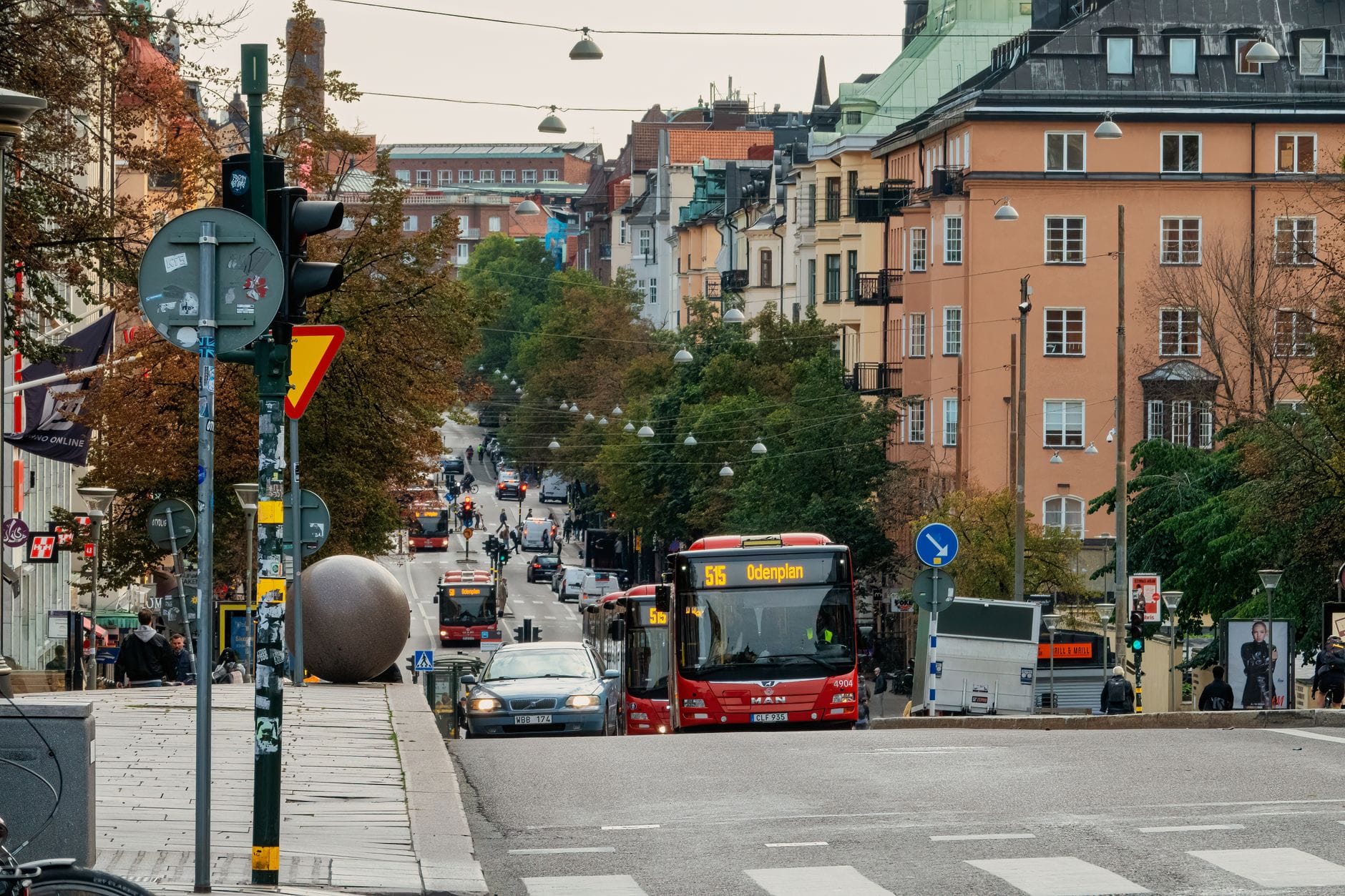 ถนนในเมืองที่คึกคักในย่านของ Stockholm พร้อมรถประจำทาง คนเดินถนน และอาคารคลาสสิกที่เรียงรายตามทางลาด