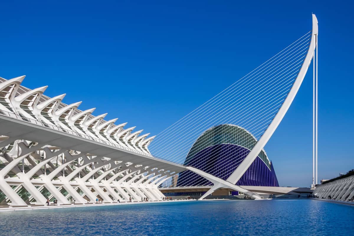 Vista amplia del complejo de la Ciudad de las Artes y las Ciencias en Valencia con impresionante arquitectura moderna, reflejos en el agua y cielo azul