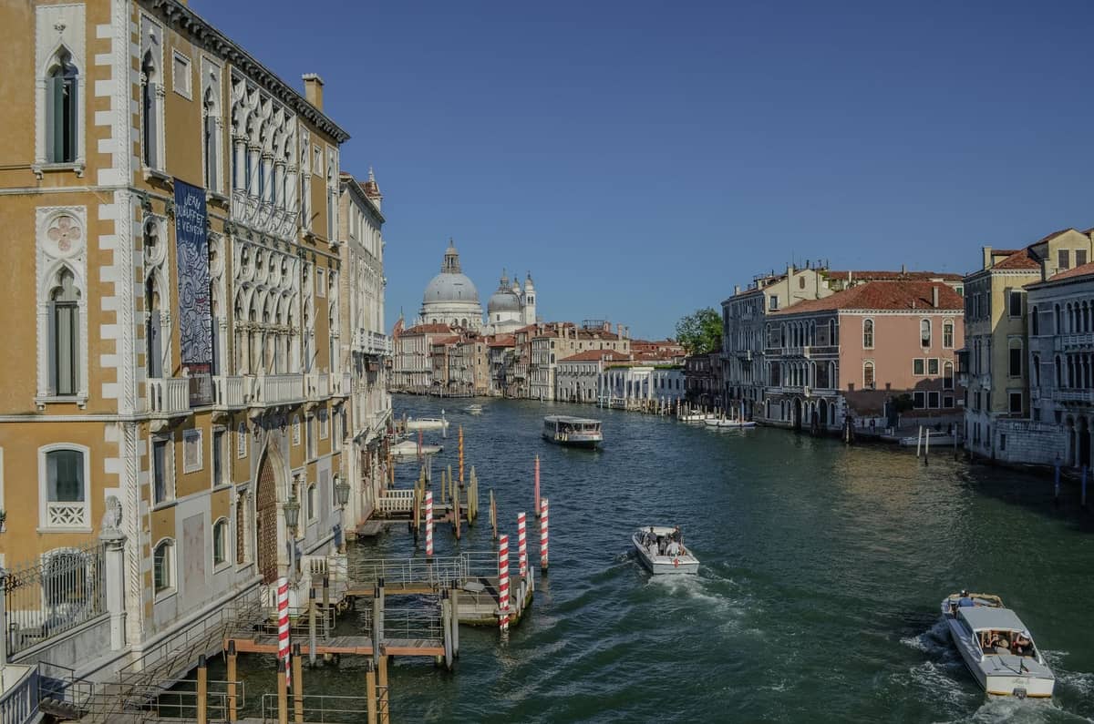 Blick auf den Canal Grande in Venedig mit den Gallerie dell'Accademia links, vorbeifahrenden Booten und den Kuppeln der Santa Maria della Salute in der Ferne.
