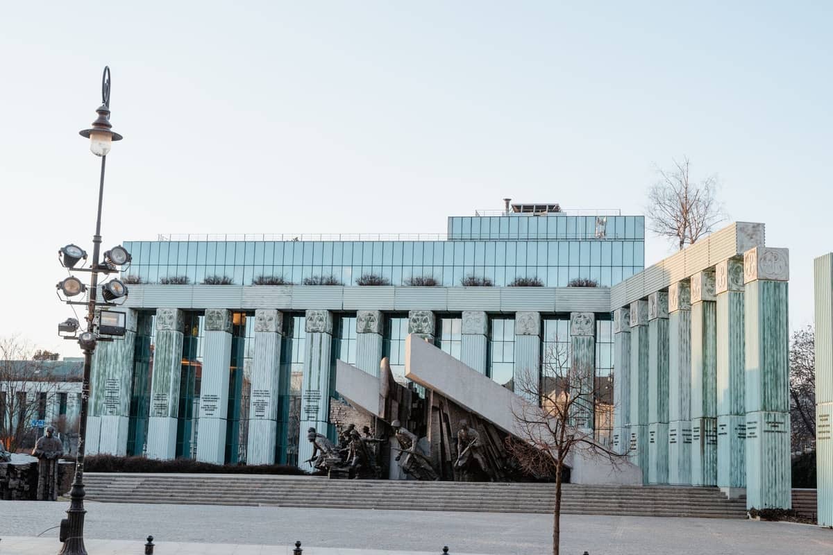Vista ampia del Monumento all'Insurrezione di Varsavia davanti al moderno edificio del museo, sotto cieli limpidi di giorno.