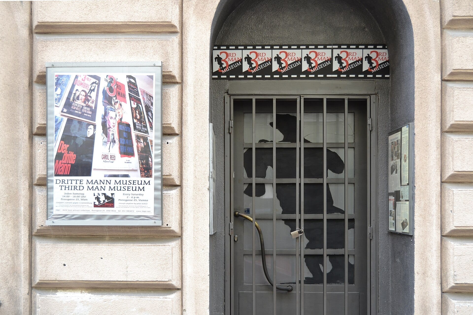 Der Eingang zum Dritten Mann Museum in Wien mit einer Filmplakatausstellung und einer Gittertür mit einer laufenden Silhouettengrafik.