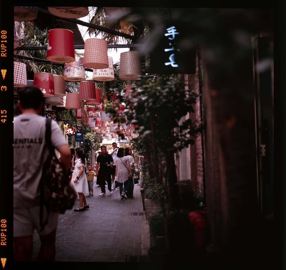 Enge Gasse in Tianzifang mit Spaziergängern und bunten Laternen darüber – das lebendige Kunst- und Einkaufsviertel in seiner ganzen Atmosphäre.