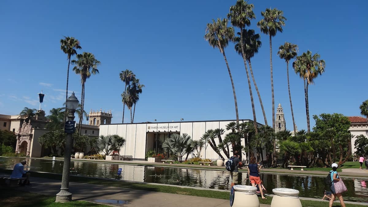 Das Timken Museum of Art im Balboa Park, umgeben von Palmen und einem spiegelnden Teich unter einem klaren blauen Himmel.