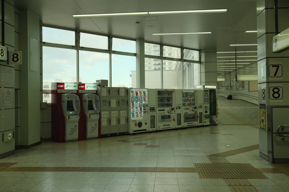 Ticket machines and vending machines inside a Japanese train or subway station with platform signs visible.