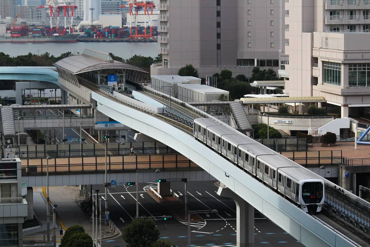 Tokyo Monorail traveling on elevated tracks through city buildings, illustrating the major rail route from Haneda Airport to central Tokyo.