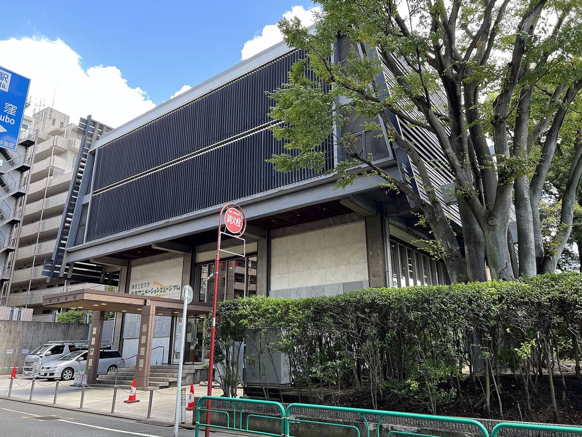 Exterior view of the Suginami Animation Museum building in Tokyo, surrounded by greenery with a clear sky above.