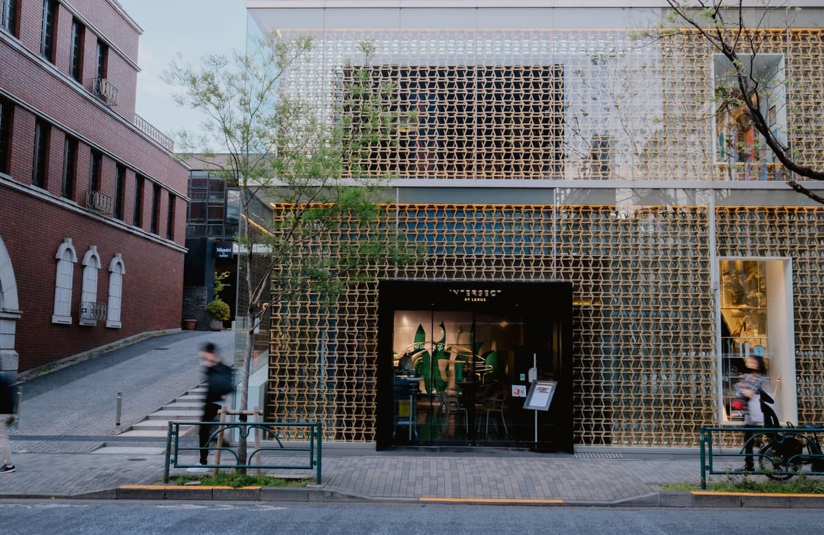 Modern Tokyo café exterior with stylish geometric facade, glass front, and people passing on the street.