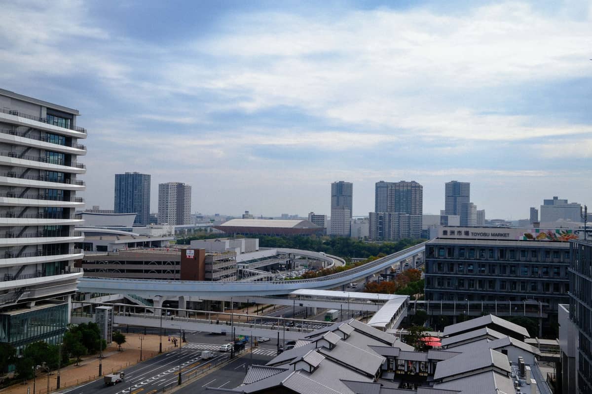 Wide view of Toyosu market buildings, elevated walkways, and modern cityscape on a cloudy day in Tokyo Bay.