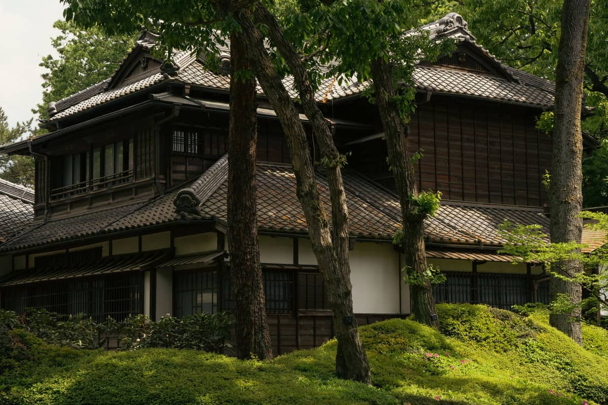 Traditional wooden Japanese mansion among trees and green gardens, characteristic of Meiji-era estates in Tokyo