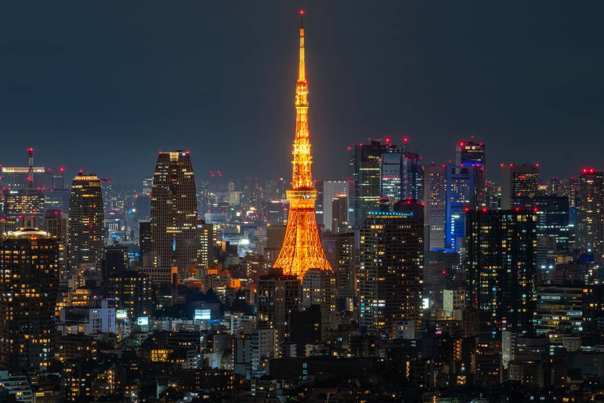 Tokyo Tower illuminated in bright orange lights, surrounded by the city skyline at night during winter.