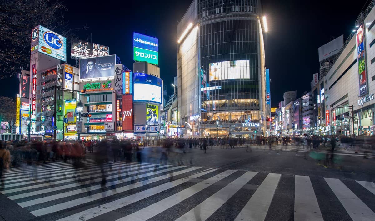 Shibuya Crossing at night with crowds crossing and tall neon-lit buildings in central Tokyo