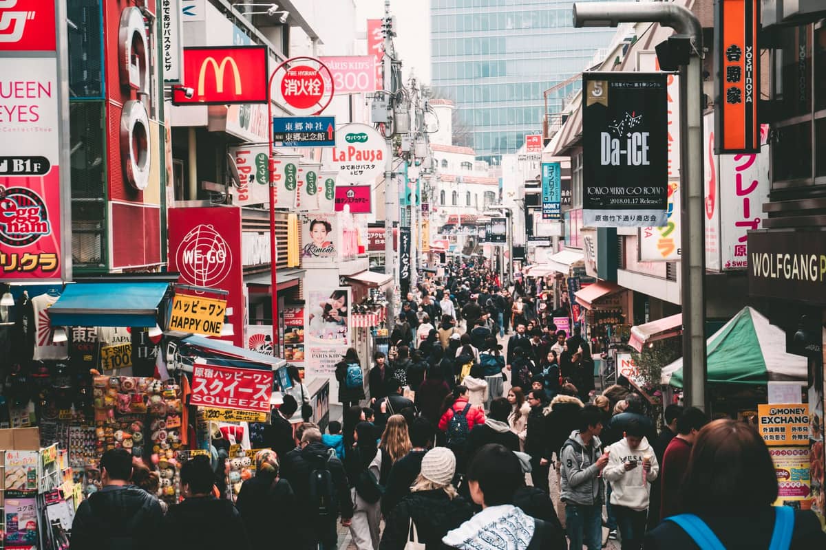 A crowded view down Takeshita Street in Harajuku, Tokyo, full of colorful shop signs, people, and vibrant stores.