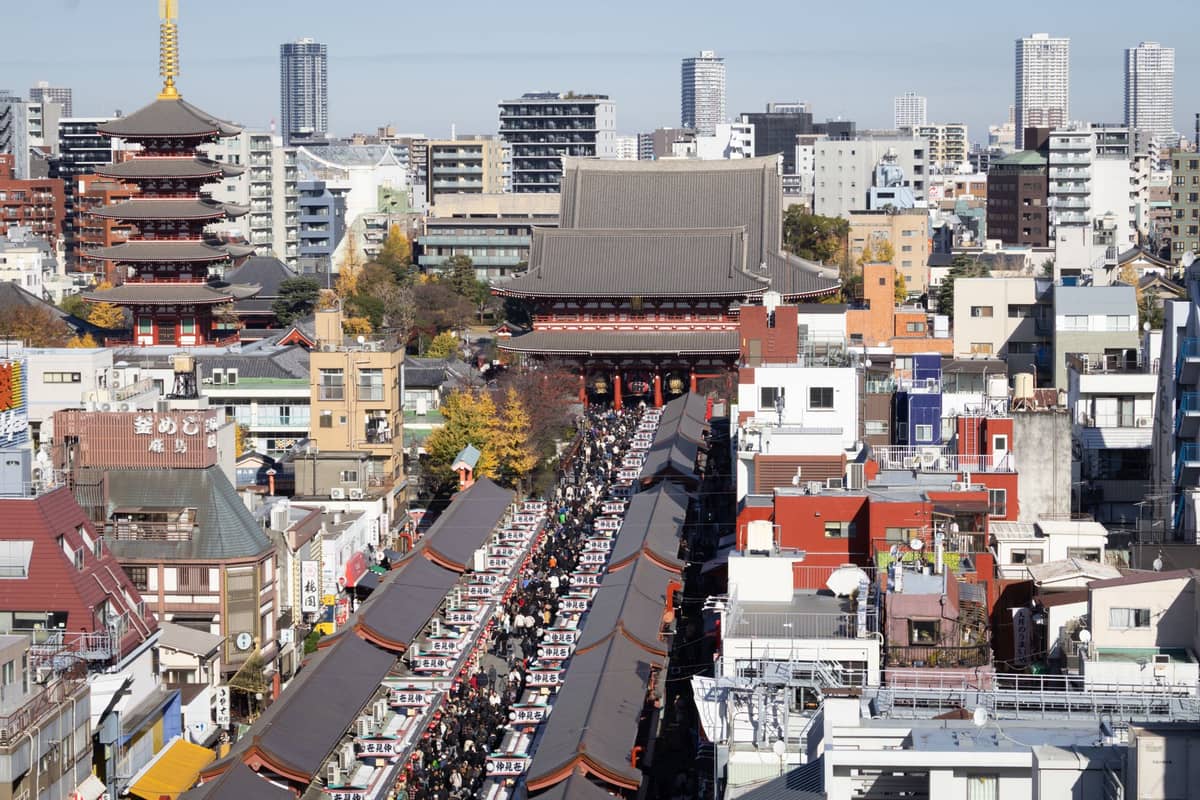 Aerial view of Tokyo’s Asakusa neighborhood with Senso-ji Temple, the Nakamise shopping street, and many city buildings in the background.